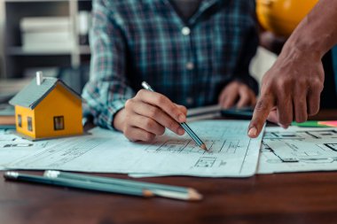 Endüstriyel mühendislerden oluşan bir ekip, makine planlarını analiz etmek için toplanıyor. Projeyi masada tartışın, ofisteki bina tasarımı projesini çizmek için dizüstü bilgisayarı kullanın. inşaat kavramı