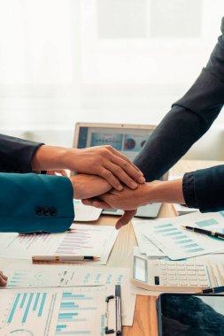 Girişimcilerin işbirliği anlaşması, modern ofiste hesap makinesi ve finansal belgelerle başarılı bir iş anlaşmasını sembolize eden ahşap masa üzerinde el sıkışıyor..