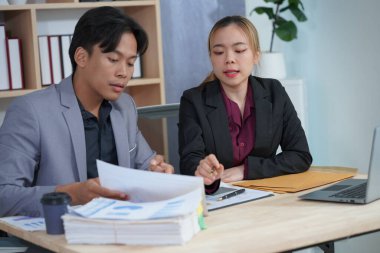 İki genç Asyalı iş adamı, başarılı bir girişim için beyin fırtınası yapmak amacıyla bir konferans odasında iş konularını tartışıyor. Ofisteki dizüstü bilgisayarlarla birlikte çalışmak