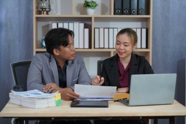 İki genç Asyalı iş adamı, başarılı bir girişim için beyin fırtınası yapmak amacıyla bir konferans odasında iş konularını tartışıyor. Ofisteki dizüstü bilgisayarlarla birlikte çalışmak