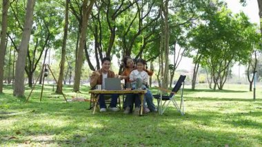 Mutlu Asyalı aile parkta kamp yapıyor, dışarıda eğleniyor, bir tatil partisini kutluyor, yemek yiyor, gitar çalıyor ve birlikte şarkı söylüyor..