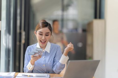 Masada oturmuş Amerikan dolarlarını sayan mutlu bir kadın elinde Amerikan dolarlarının hayranı, gülümseyen bir işadamı mali başarısını kutluyor.