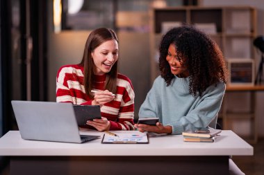 Takım çalışması laptoplu iki kadın makaleler, iş birlikleri ve mesai sonrası toplantılar için araştırma yapıyorlar..