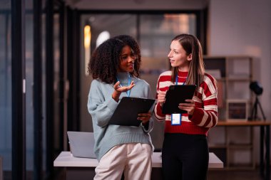 Takım çalışması laptoplu iki kadın makaleler, iş birlikleri ve mesai sonrası toplantılar için araştırma yapıyorlar..