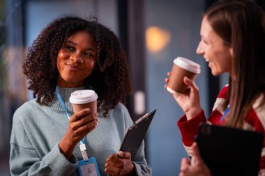 Takım çalışması laptoplu iki kadın makaleler, iş birlikleri ve mesai sonrası toplantılar için araştırma yapıyorlar..