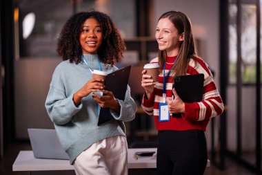 Takım çalışması laptoplu iki kadın makaleler, iş birlikleri ve mesai sonrası toplantılar için araştırma yapıyorlar..