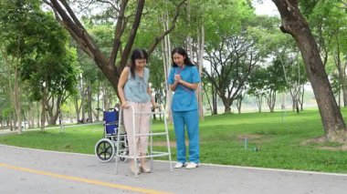 Elinde baston tutan yaşlı bir kadın parkta bir kadın hemşire tarafından bakılıyor, doğal terapi konsepti, yaşlılar için çalışan ya da bakıcı