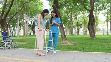 Elinde baston tutan yaşlı bir kadın parkta bir kadın hemşire tarafından bakılıyor, doğal terapi konsepti, yaşlılar için çalışan ya da bakıcı