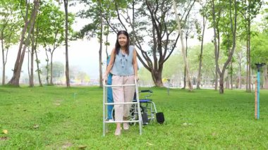 Elinde baston tutan yaşlı bir kadın parkta bir kadın hemşire tarafından bakılıyor, doğal terapi konsepti, yaşlılar için çalışan ya da bakıcı