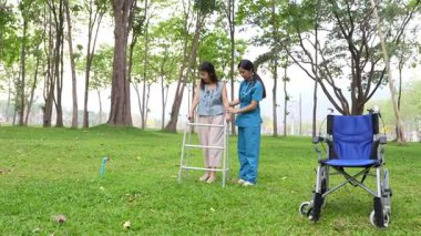 Genç bir Asyalı doktor yaşlı bir kadını parkta yürüyüşe çıkarıyor. Doğal terapi konsepti. Yaşlıların bakıcısı veya çalışanı.