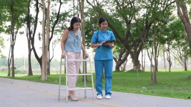 Genç bir Asyalı doktor yaşlı bir kadını parkta yürüyüşe çıkarıyor. Doğal terapi konsepti. Yaşlıların bakıcısı veya çalışanı.