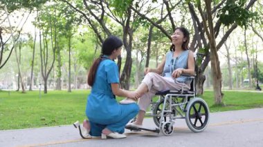 Tekerlekli sandalyede oturan ve parkta kadın bir hemşire tarafından bakılan yaşlı bir kadın. Doğal terapi konsepti. Ya da yaşlıların bakıcıları.