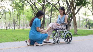 Tekerlekli sandalyede oturan ve parkta kadın bir hemşire tarafından bakılan yaşlı bir kadın. Doğal terapi konsepti. Ya da yaşlıların bakıcıları.