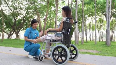 Tekerlekli sandalyede oturan ve parkta kadın bir hemşire tarafından bakılan yaşlı bir kadın. Doğal terapi konsepti. Ya da yaşlıların bakıcıları.