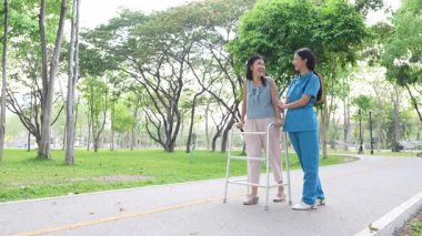 Genç bir Asyalı doktor yaşlı bir kadını parkta yürüyüşe çıkarıyor. Doğal terapi konsepti. Yaşlıların bakıcısı veya çalışanı.