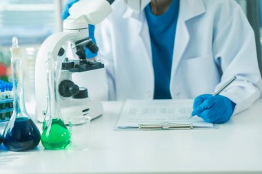 Bilimadamları ve mikroskoplar tıbbi araştırmalar, yenilikler veya aşı laboratuvarlarında analizler için.