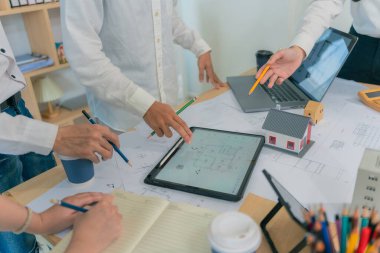 İnşaat konsepti mimarı ya da mühendisi inşaat planıyla masada tartışıyor. Mühendis mimari planlamak için işyerini teftiş ediyor. İnşaat projesi taslağı. Kapat..