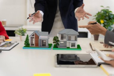 Müşteri kontratı, para ve belgeler imzalayan emlakçı. Modellerle aynı masada müşteriyle ev sigortası hakkında konuşuyor. Ev sigortası kavramı.