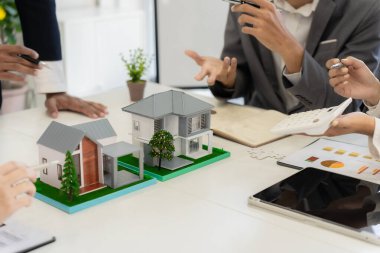 Müşteri kontratı, para ve belgeler imzalayan emlakçı. Modellerle aynı masada müşteriyle ev sigortası hakkında konuşuyor. Ev sigortası kavramı.