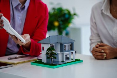 Müşteri kontratı, para ve belgeler imzalayan emlakçı. Modellerle aynı masada müşteriyle ev sigortası hakkında konuşuyor. Ev sigortası kavramı.
