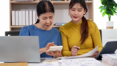 Yaşlı kadın ve Asyalı kadın evde muhasebe belgeleri üzerinde birlikte çalışıyorlar. Anne bilgisayarın nasıl kullanılacağını öğreniyor ya da evdeki kızından internet üzerinden teknoloji bilgisi arıyor..