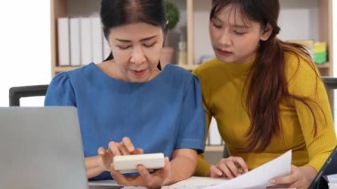 Yaşlı kadın ve Asyalı kadın evde muhasebe belgeleri üzerinde birlikte çalışıyorlar. Anne bilgisayarın nasıl kullanılacağını öğreniyor ya da evdeki kızından internet üzerinden teknoloji bilgisi arıyor..
