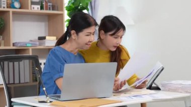 Yaşlı kadın ve Asyalı kadın evde muhasebe belgeleri üzerinde birlikte çalışıyorlar. Anne bilgisayarın nasıl kullanılacağını öğreniyor ya da evdeki kızından internet üzerinden teknoloji bilgisi arıyor..