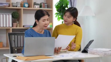 Yaşlı kadın ve Asyalı kadın evde muhasebe belgeleri üzerinde birlikte çalışıyorlar. Anne bilgisayarın nasıl kullanılacağını öğreniyor ya da evdeki kızından internet üzerinden teknoloji bilgisi arıyor..