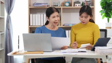 Yaşlı kadın ve Asyalı kadın evde muhasebe belgeleri üzerinde birlikte çalışıyorlar. Anne bilgisayarın nasıl kullanılacağını öğreniyor ya da evdeki kızından internet üzerinden teknoloji bilgisi arıyor..