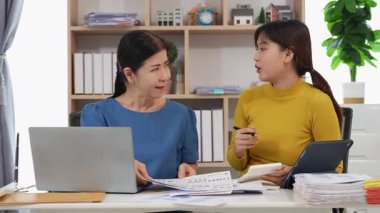 Yaşlı kadın ve Asyalı kadın evde muhasebe belgeleri üzerinde birlikte çalışıyorlar. Anne bilgisayarın nasıl kullanılacağını öğreniyor ya da evdeki kızından internet üzerinden teknoloji bilgisi arıyor..