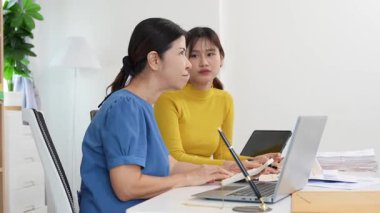 Yaşlı kadın ve Asyalı kadın evde muhasebe belgeleri üzerinde birlikte çalışıyorlar. Anne bilgisayarın nasıl kullanılacağını öğreniyor ya da evdeki kızından internet üzerinden teknoloji bilgisi arıyor..