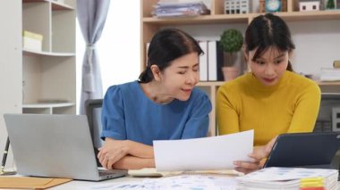 Yaşlı kadın ve Asyalı kadın evde muhasebe belgeleri üzerinde birlikte çalışıyorlar. Anne bilgisayarın nasıl kullanılacağını öğreniyor ya da evdeki kızından internet üzerinden teknoloji bilgisi arıyor..