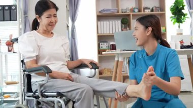 Asyalı kadın doktor yaşlı kadın hastalarla ilgilenir, fizik tedaviye yardım eder, lastik tüplerle esnetir, ve sağlık, danışmanlık ve egzersiz için diz ağrısı, spor yaralanmaları,.
