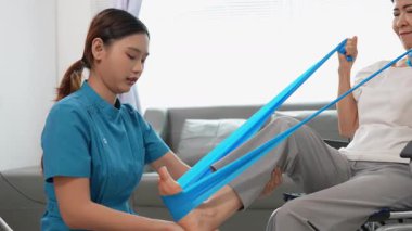 Asyalı kadın doktor yaşlı kadın hastalarla ilgilenir, fizik tedaviye yardım eder, lastik tüplerle esnetir, ve sağlık, danışmanlık ve egzersiz için diz ağrısı, spor yaralanmaları,.