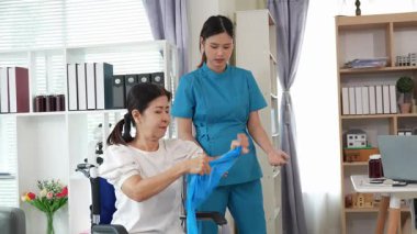 Asyalı kadın doktor yaşlı kadın hastalarla ilgilenir, fizik tedaviye yardım eder, lastik tüplerle esnetir, ve sağlık, danışmanlık ve egzersiz için diz ağrısı, spor yaralanmaları,.