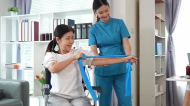 Asyalı kadın doktor yaşlı kadın hastalarla ilgilenir, fizik tedaviye yardım eder, lastik tüplerle esnetir, ve sağlık, danışmanlık ve egzersiz için diz ağrısı, spor yaralanmaları,.