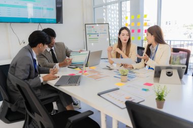 Profesyonel bir ekip, bir ofis konferans odasında gerçekleşen toplantı sırasında stratejik planlama ve karar verme süreçlerine ilişkin verileri analiz etmek üzere mali tabloları gözden geçiriyor ve birlikte çalışıyor..