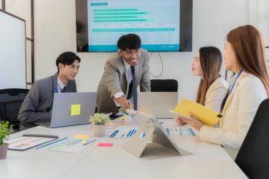 Profesyonel bir ekip, bir ofis konferans odasında gerçekleşen toplantı sırasında stratejik planlama ve karar verme süreçlerine ilişkin verileri analiz etmek üzere mali tabloları gözden geçiriyor ve birlikte çalışıyor..