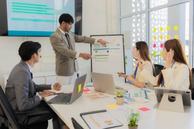 Profesyonel bir ekip, bir ofis konferans odasında gerçekleşen toplantı sırasında stratejik planlama ve karar verme süreçlerine ilişkin verileri analiz etmek üzere mali tabloları gözden geçiriyor ve birlikte çalışıyor..