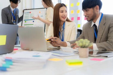Profesyonel bir ekip, bir ofis konferans odasında gerçekleşen toplantı sırasında stratejik planlama ve karar verme süreçlerine ilişkin verileri analiz etmek üzere mali tabloları gözden geçiriyor ve birlikte çalışıyor..