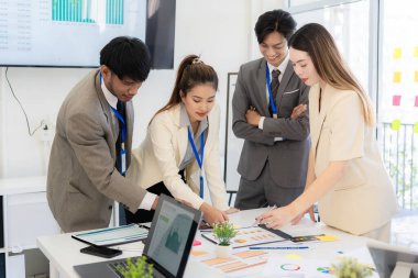 Profesyonel bir ekip, bir ofis konferans odasında gerçekleşen toplantı sırasında stratejik planlama ve karar verme süreçlerine ilişkin verileri analiz etmek üzere mali tabloları gözden geçiriyor ve birlikte çalışıyor..
