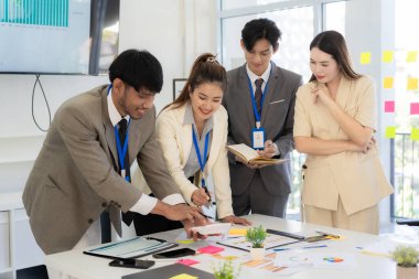 Profesyonel bir ekip, bir ofis konferans odasında gerçekleşen toplantı sırasında stratejik planlama ve karar verme süreçlerine ilişkin verileri analiz etmek üzere mali tabloları gözden geçiriyor ve birlikte çalışıyor..