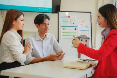 Asyalı kadın emlakçı anlaşmayı açıklıyor ve yeni bir ev almak üzere olan çifte emlak satışı için ev sahibiyle görüşüyor..