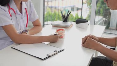 Yaşlı bir Asyalı diş sorunlarını tartışmak için dişçiye gider. Kadın bir doktor klinikte oturmuş yaşlı bir Asyalı adama diş ağrısından bahsediyor..