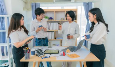 Genç Asyalı mimarlardan oluşan bir ekip, ofis, takım çalışması ve sanayi konsepti üzerinde çalışma planları ve inşaat araçları kullanarak yeni bir proje planlıyor..