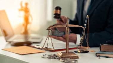 Masasında teraziyle, çekiciyle ve küçük tahta oyuncak eviyle oturan, belgelerle çalışan, kontrat imzalayan, gayrimenkul yasası olan, ödenmesi mümkün olmayan hacizli mallarla uğraşan bir avukat..