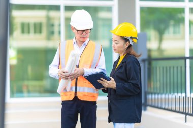 Proje yöneticisi, köy emlak şirketindeki yol yapım çalışmalarının ilerlemesini kontrol etmek için asistanına danışıyor..