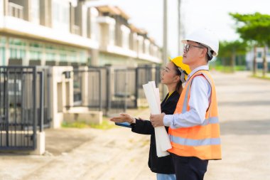 İki Asyalı erkek ve kadın mühendis işi inceliyor. İki kadın mimar, erkek bir mühendis ile birlikte binayı inceliyor..