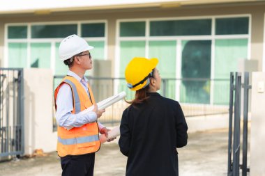 İki Asyalı erkek ve kadın mühendis işi inceliyor. İki kadın mimar, erkek bir mühendis ile birlikte binayı inceliyor..