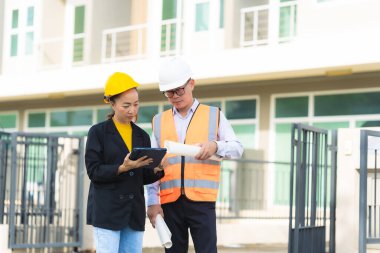 İki Asyalı erkek ve kadın mühendis işi inceliyor. İki kadın mimar, erkek bir mühendis ile birlikte binayı inceliyor..